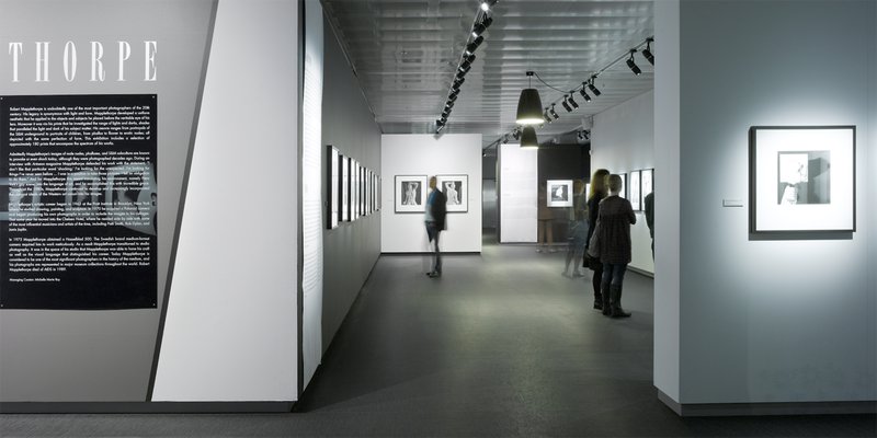 One of the exhibition- halls at the museum for modern photography, Fotografiska in Stockholm. Visitors are looking around in a white, stark gallery space.