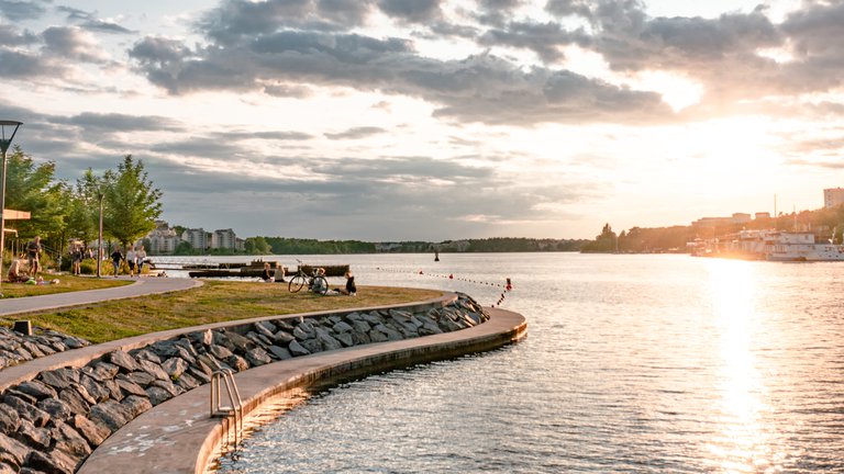 Sommar i Stockholm. Hornsbergs strand. Människor sitter vid Mälarens vatten, njuter av en vacker sommar kväll.