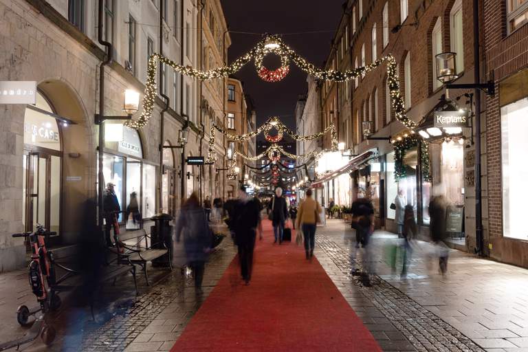 Männikskor går på shoppinggatan Biblioteksgatan, som dekorerats med julbelysning i form av stora kransar