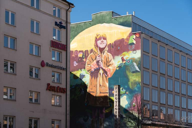 Street art i Stockholm. En stor mural på Södermalm i Stockholm. Graffitimålningen föreställer en ung flicka i gula regnkläder som håller i ett gult paraply.