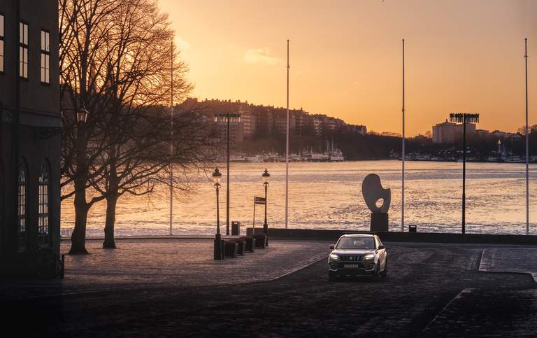 Resa i Stockholm. Personbil åker på Riddarholmen i solnedgång.
