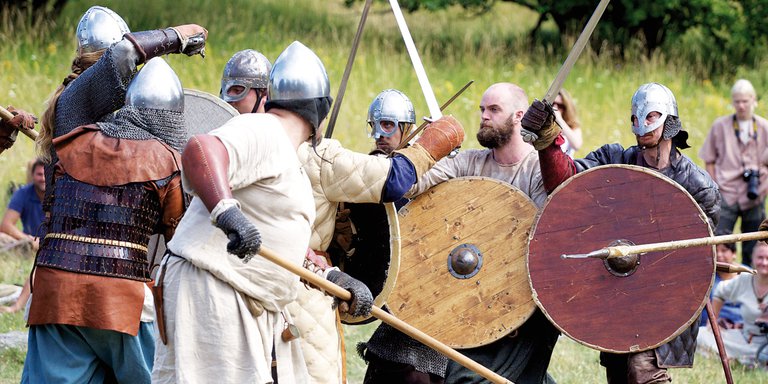 Vikingar i Sverige. Skådespelare spelar upp ett vikingaslag inför publik. Skådespelarna har svärd och sköld, och är klädda i hjälm och brynja. Det finns flera bra sevärdheter i Stockholmstrakten för den historieintresserade som vill lära sig mer om vikingar.