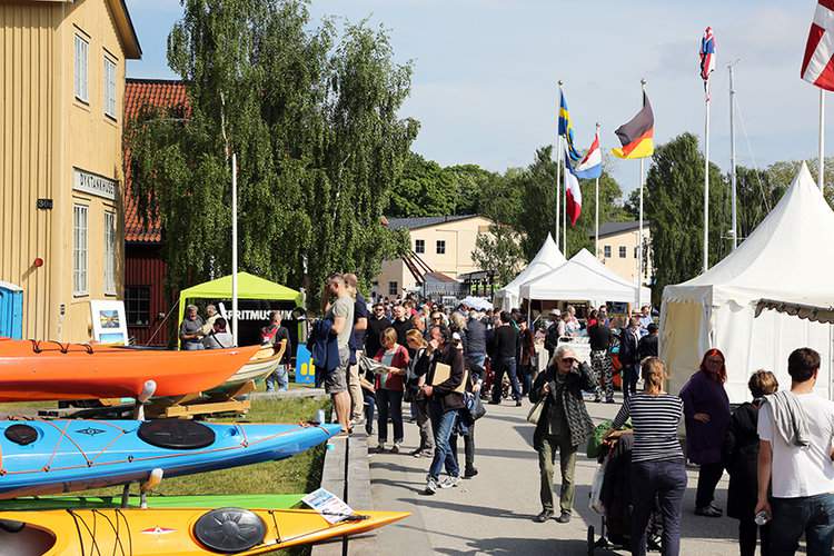 Människor som pomenerar bland mässstånd en sommardag.