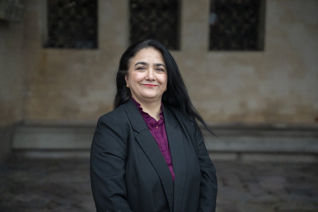 Dr Alia Amir utomhus framför en stenbyggnad.