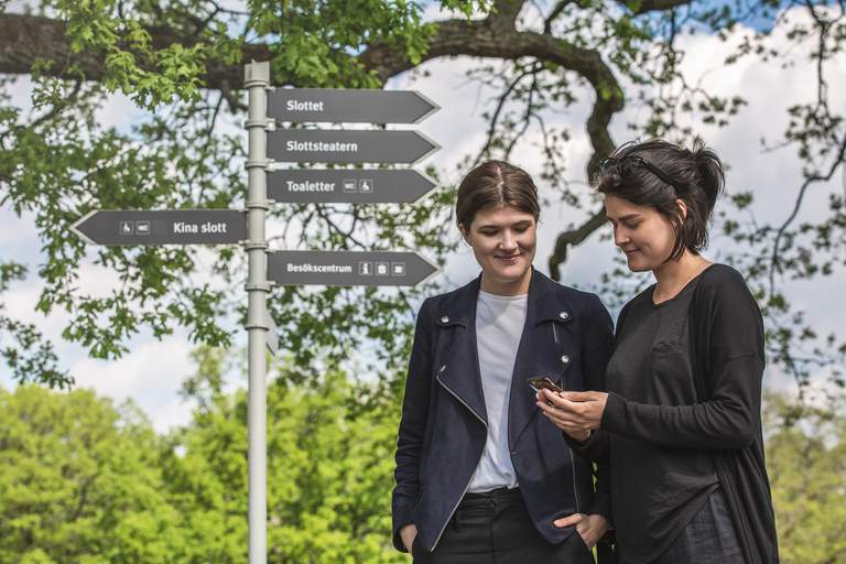 Två personer som tittar på en mobiltelefon i en park.