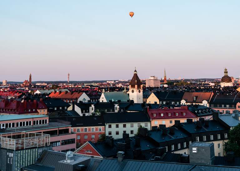 Vacker utsikt över Stockholms takåsar med en luftballong svävande i den blå skyn