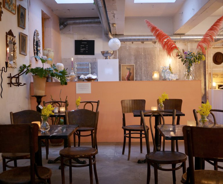Ett café: bord, stolar, blommor, tavlor på väggarna.