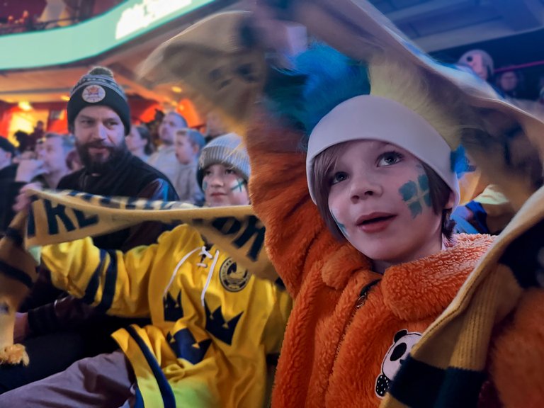 Hockeyfans i matchställ som kollar på en match.