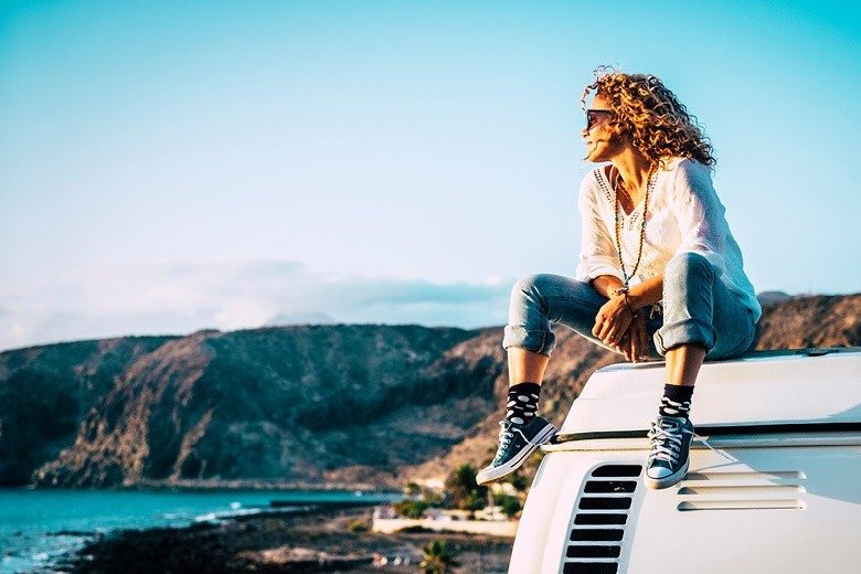 Person sitter på en husbil med utsikt över hav och klippig kust.