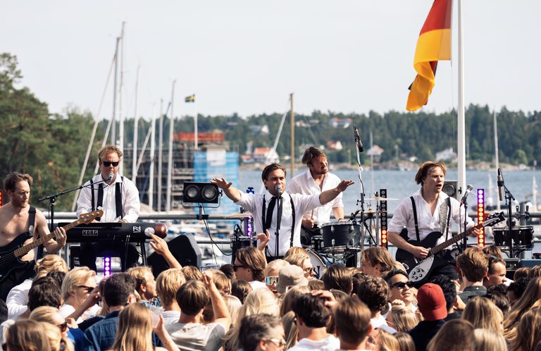 Musiker som spelar på en scen utomhus.