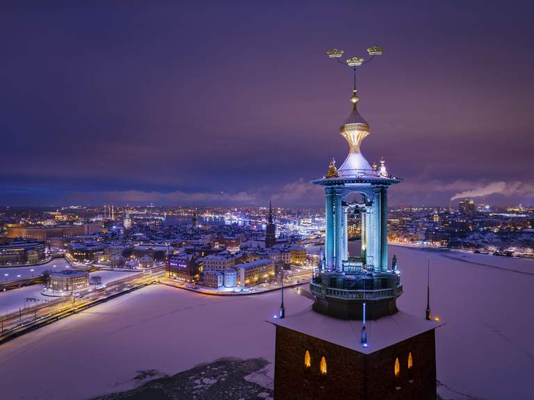 Stockholms Stadshustorn med sina gyllene kronor syns i förgrunden i detta flygfoto över Stockholms innerstad en klar vinternatt, med ett flertal bebyggda öar omgivna av vatten
