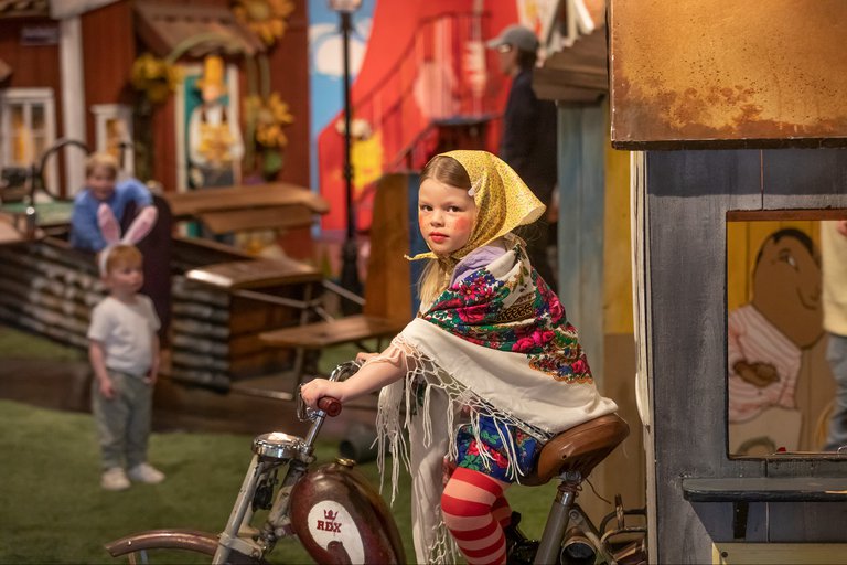 flicka utklädd till påsk-kärring sitter på en cykel
