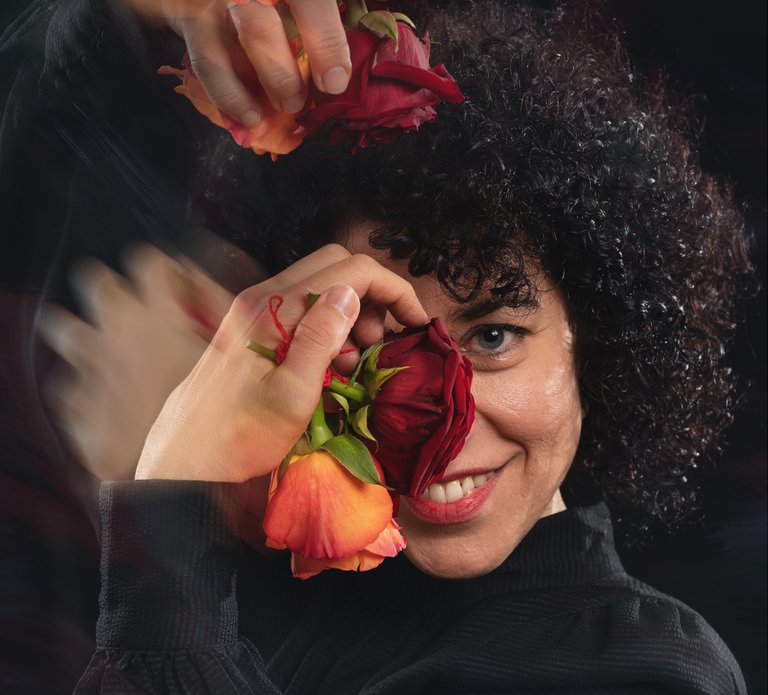 En leende kvinna med rosor i händerna.
