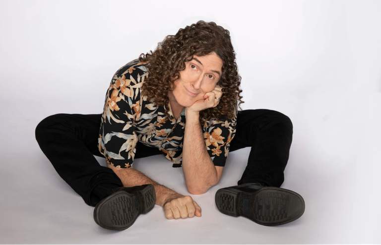 Artisten "Weird Al" Yankovic som sitter på golvet.