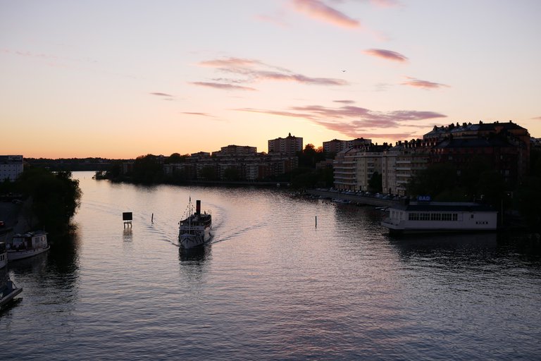 Vår i Stockholm. En båt trafikerar i vattnen nedanför LIljeholmsbron.