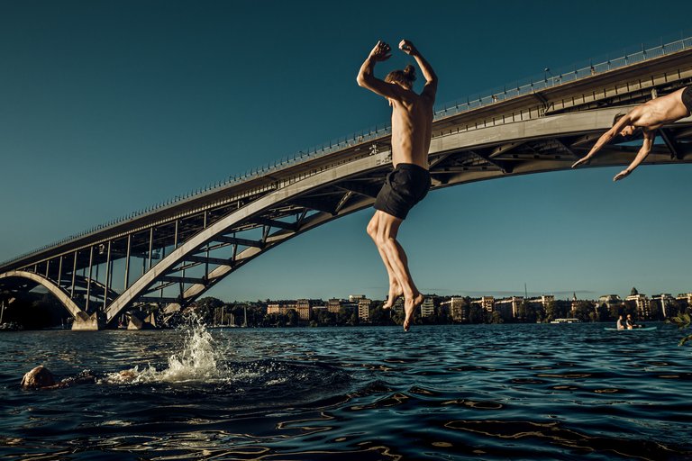Friends taking a swim and jump into the water of Stockholm