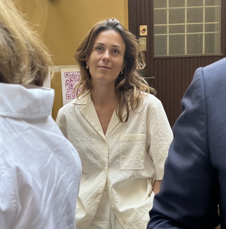 Therese Cappelen står vid en dörr samtidigt som två personer minglar i framkant.