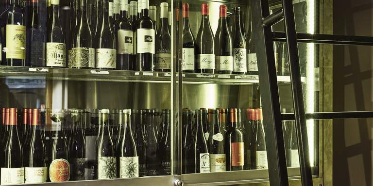 Ett kabinett fullt av vinflaskor på Tyge och Sesil, en vinbar i Stockholm. Rött, vitt, rosé eller mousserande: det finns många bra ställen i Stockholm att dricka ett glas vin som har valts med omsorg.