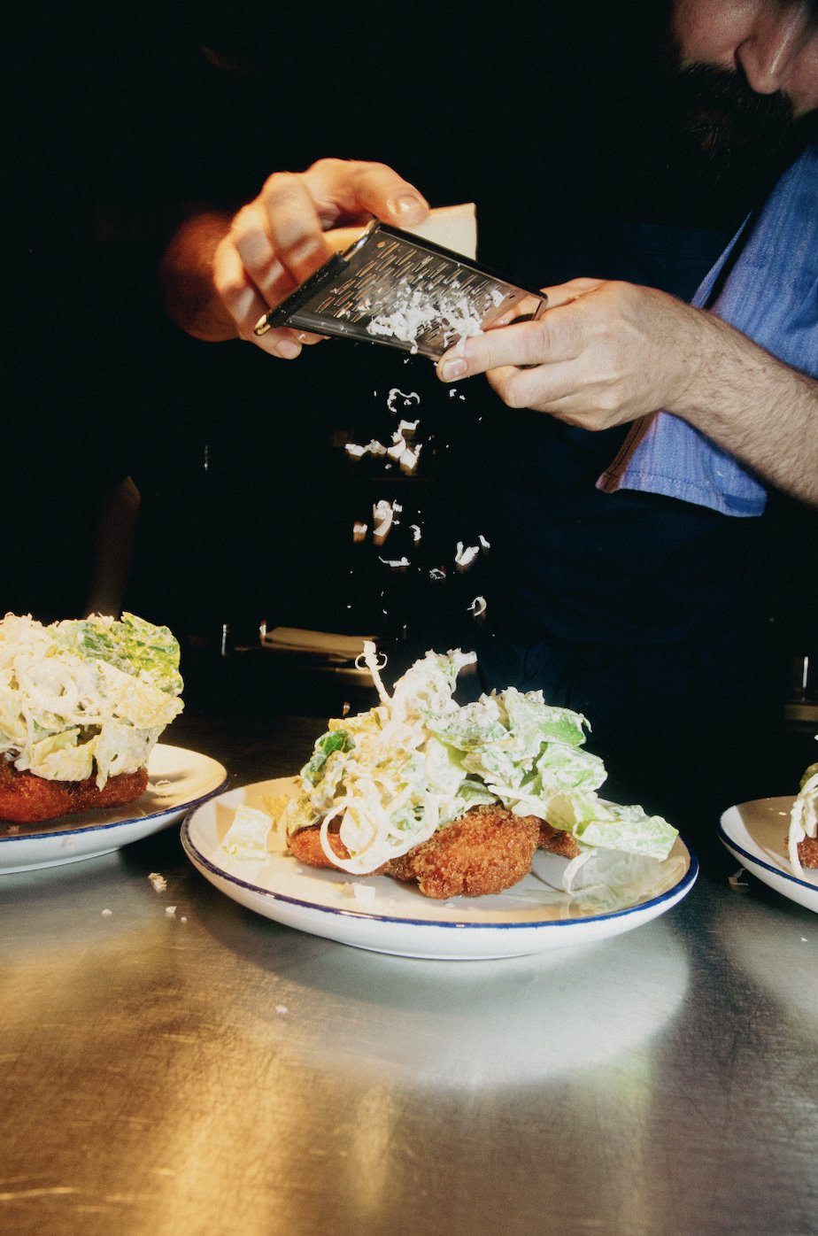 Händer som river ost över en tallrik med mat