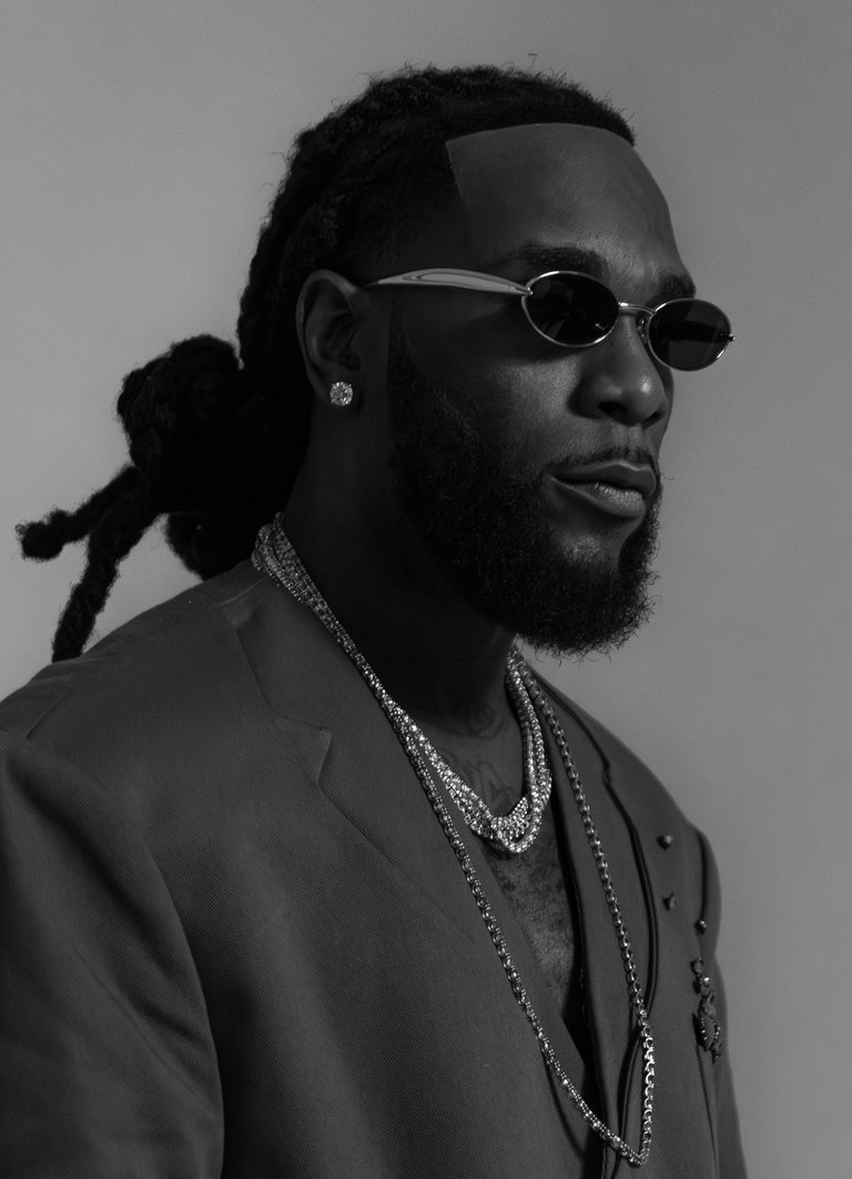 En man med kavaj, solglasögon och diverse smycken.