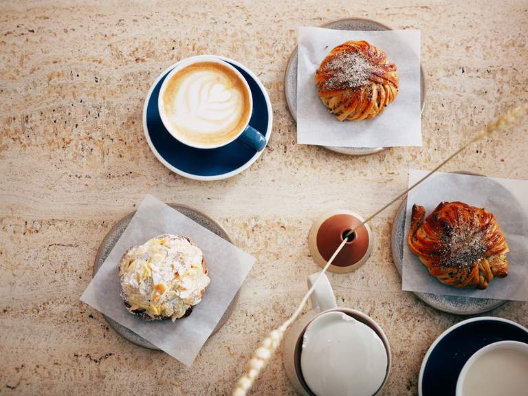 Cafeer i Stockholm. Ett bord är dukar för fika, kaffe och bullar, på Café Pascal på Södermalm.