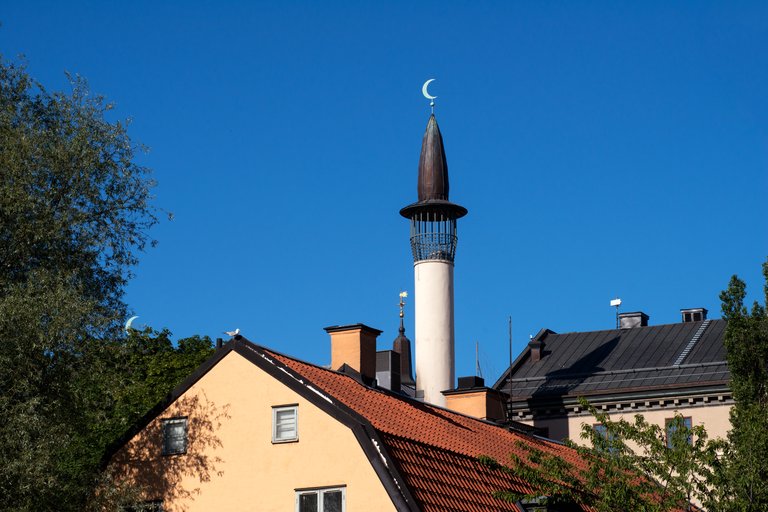 Stockholms moské med minareten och halvmånen mot en klarblå himmel.