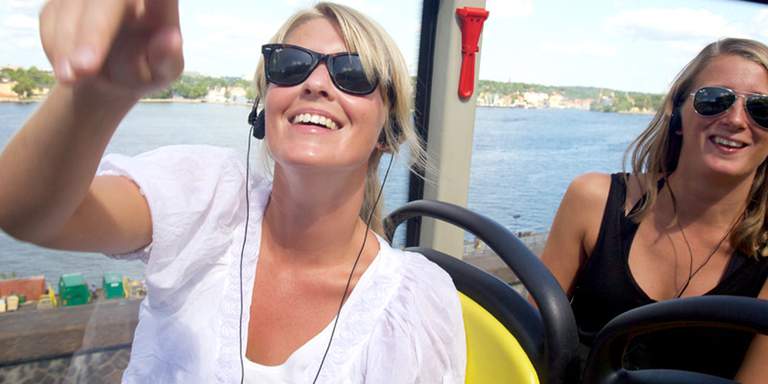 Kvinnor åker sightseeingbuss i Stockholm.