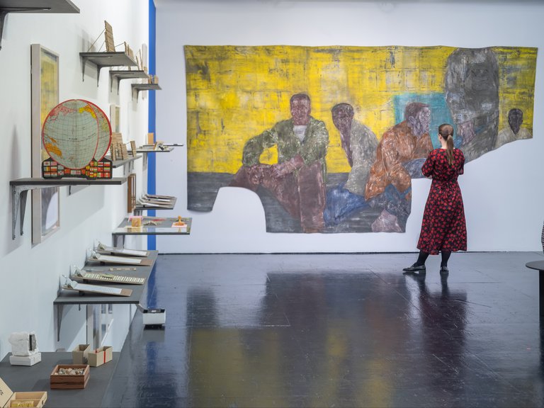 Museer i Stockholm. En kvinna står framför en tavla på Tensta konsthall. Tavlan är "Fångar II" (1989) av Leon Golub.)