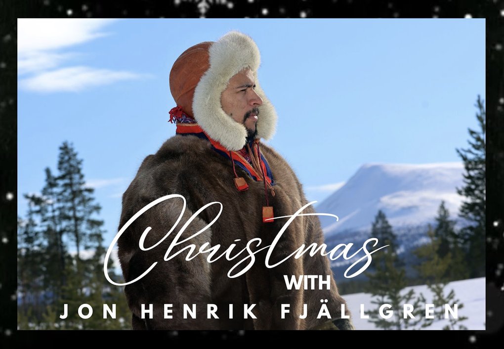 En man i pälskläder står i profil ett snölandskap med orden "Christmas with Jon Henrik Fjällgren" i förgrunden.
