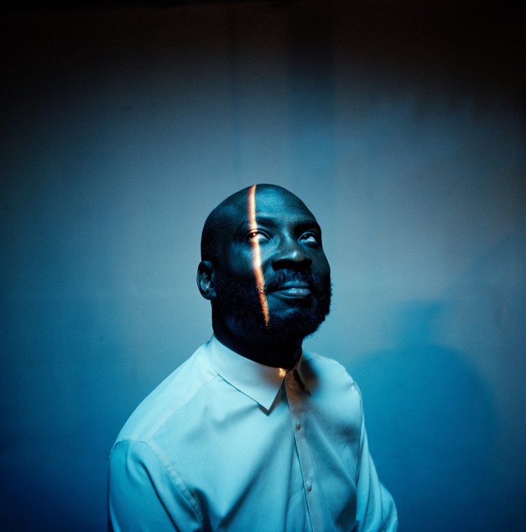 En man i vit skjorta tittar upp mot ljuset som lyser ned på hans ansikte.