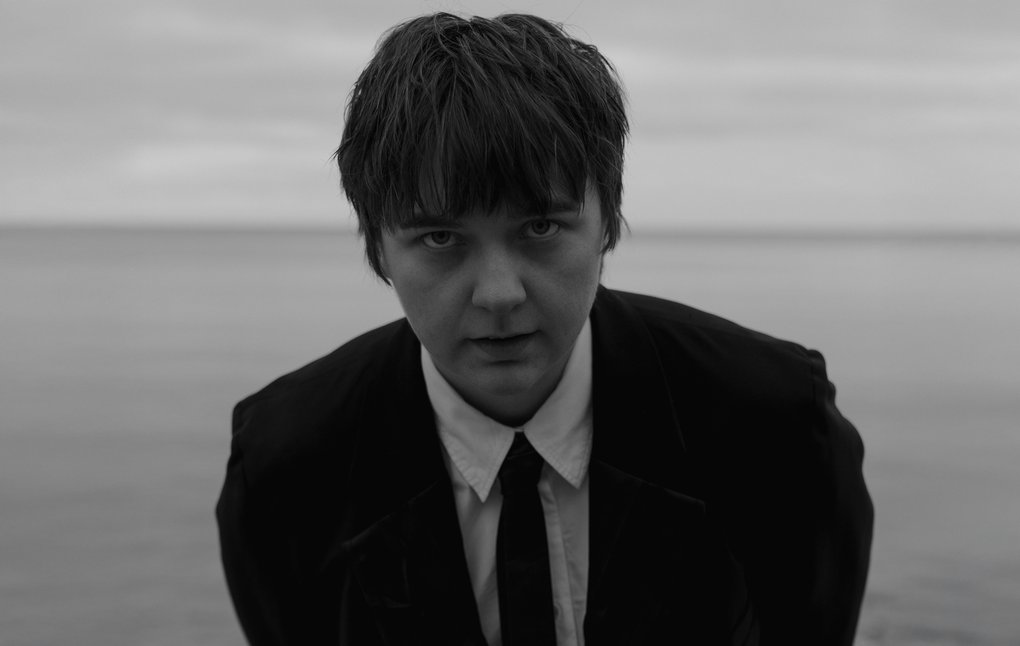 Kerstin Ljungström står vid havet, iklädd kostym och slips.