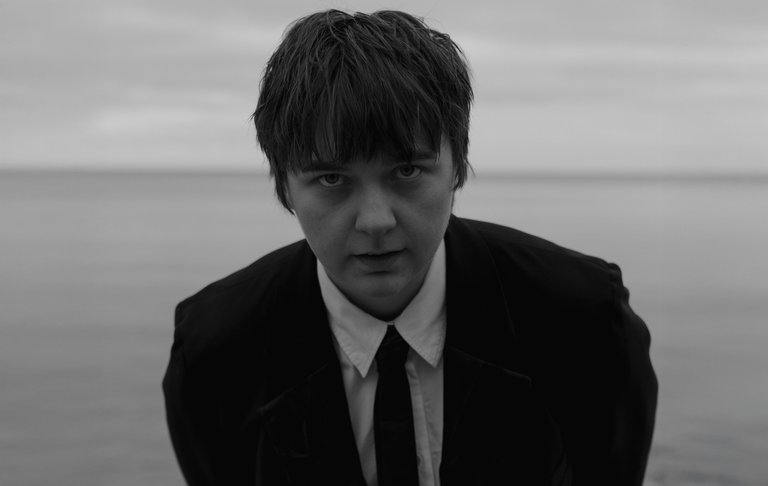 Kerstin Ljungström står vid havet, iklädd kostym och slips.