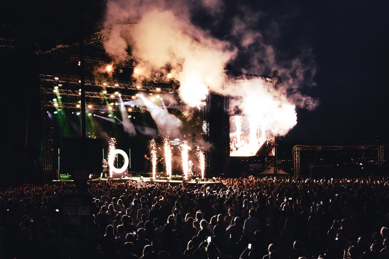 Publiken står framför stora scenen på Stockholms Kulturfestival. Kväll. Pyroteknik lyser upp artisten som framträder på scenen.
