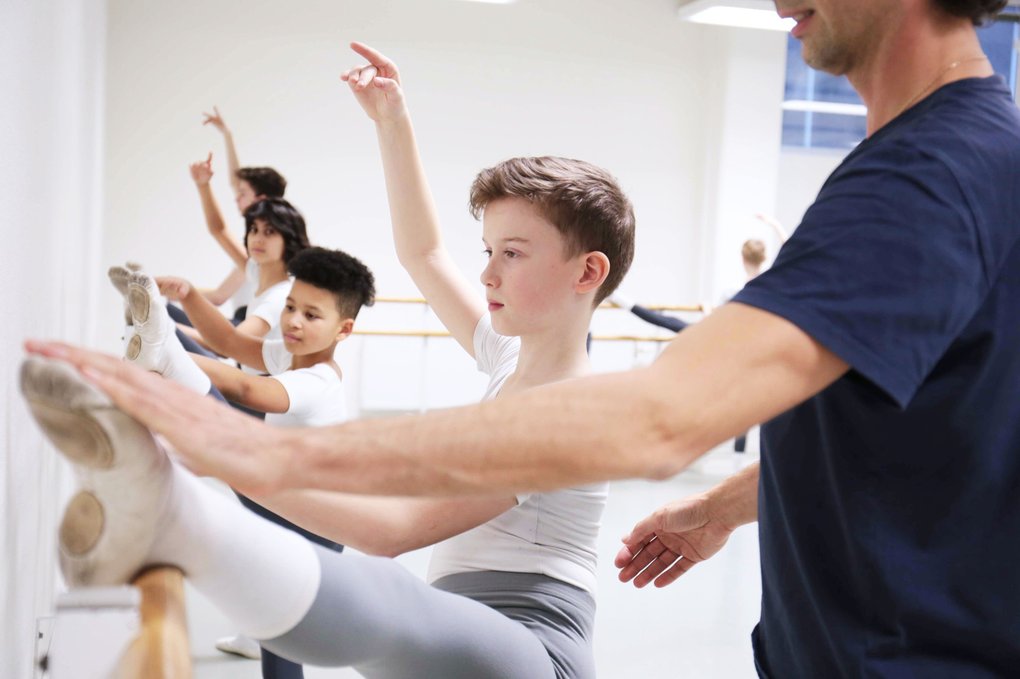 Balettlärare guidar elever som tränar vid stången på Kungliga Svenska Balettskolan.