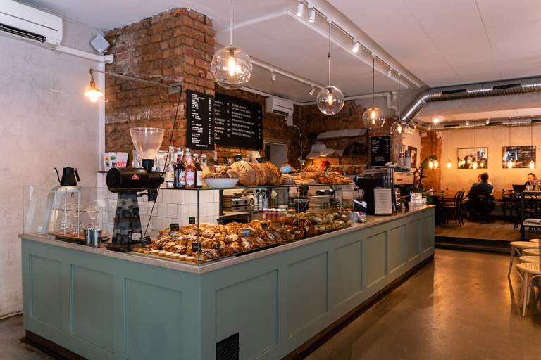 Cafées in Stockholm. Café Pascal i Vasastan. Människor sitter på det populära Café Pascal vid Odenplan. Inredningen är ljus och rustik. I bild syns caféets disk, fylld av bullar, croisanter och andra bakverk.