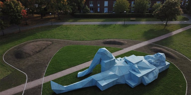 Public art in Stockholm Vårbergs jättar by Xavier Veilhan in Vårberg. Pictured is a large statue of a man, lying on his back and resting.