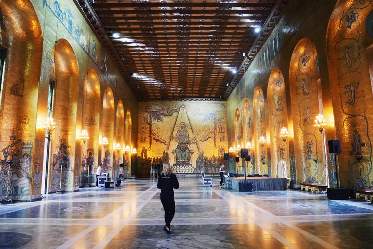 Sevärdheter i Stockholm. Gyllene salen i Stockholms stadshus. Ett gyllene rum med högt tak. På bakre väggen syns en stor mosaik av St. Erik.