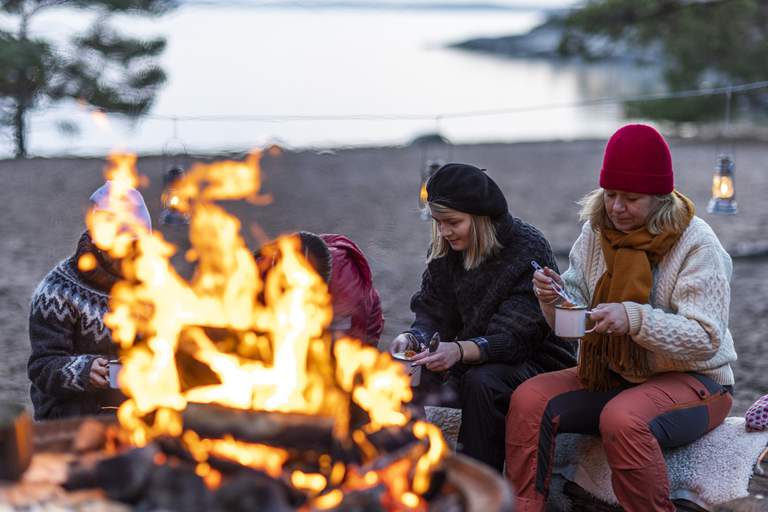 Vinter i skärgården. En familj äter middag vid en brasa på Björnö.