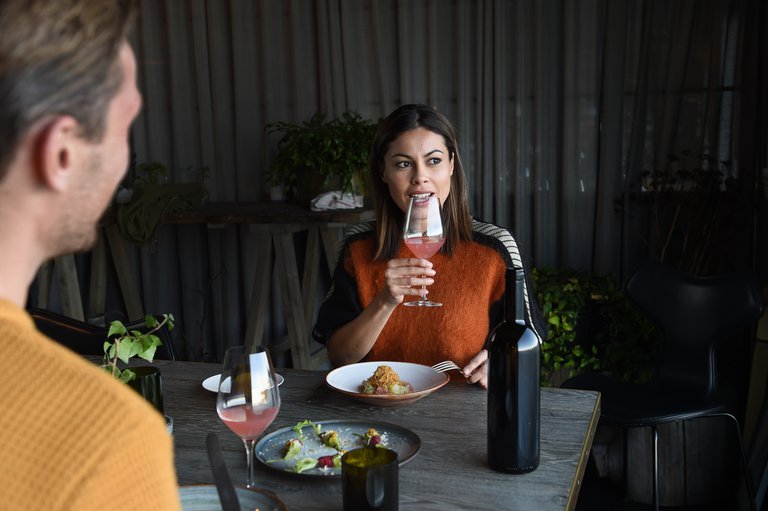 Woman and man sitting down and enjoying a dinner at a restaurant.