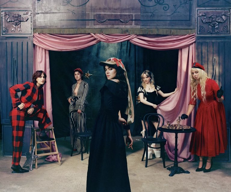 De fem medlemmarna i The Last Dinner Party poserar på en teaterscen i anakronistiska kläder.