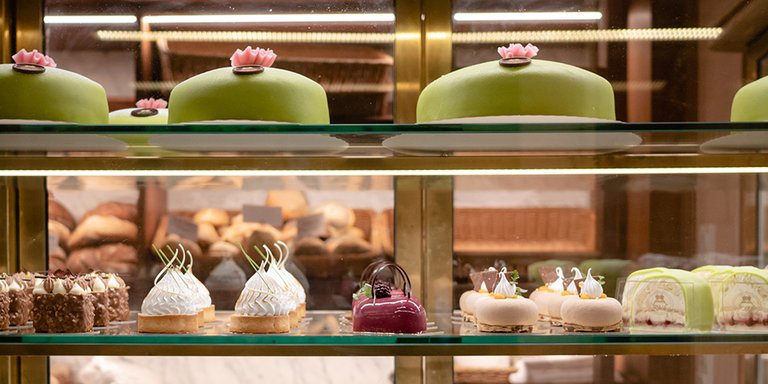 Disk med eleganta bakelser och tårtor i ett konditori i Stockholm, med klassiska marsipantårtor och små bakverk i olika färger.