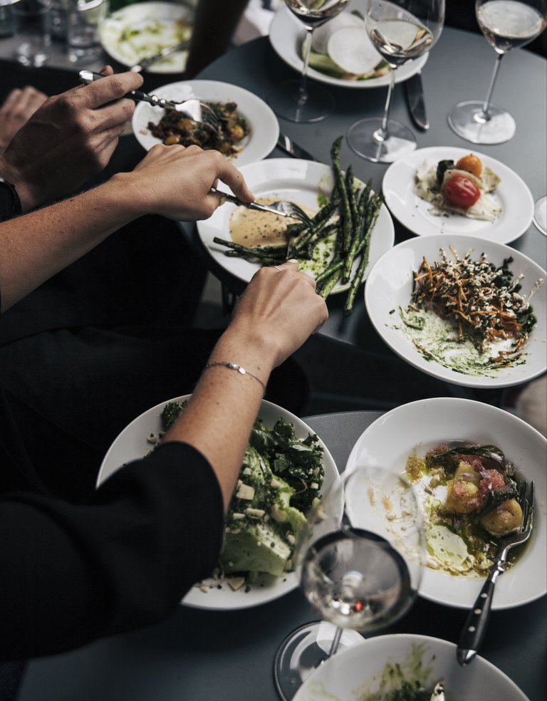 Mat i Stockholm. Ett par händer skär i mat som ligger på en talrik.